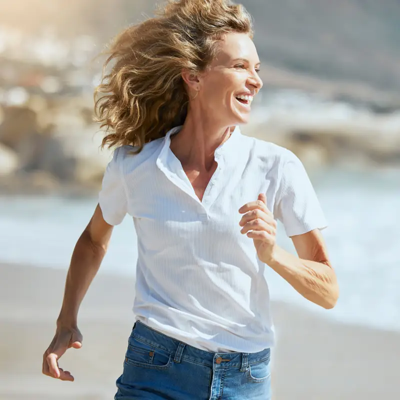 mujer 50 feliz corriendo playa