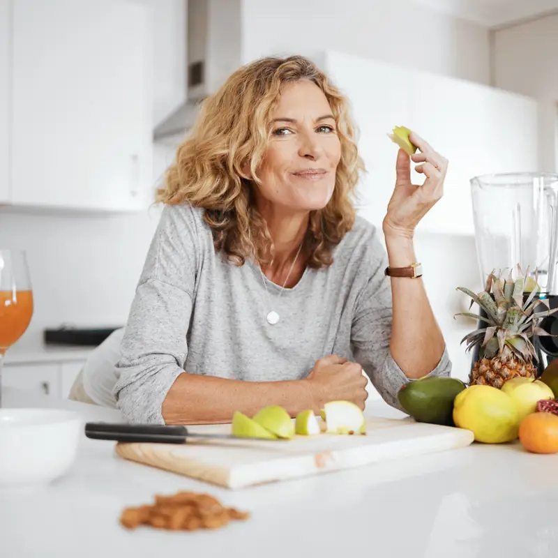 mujer 50 sonriendo comiendo fruta