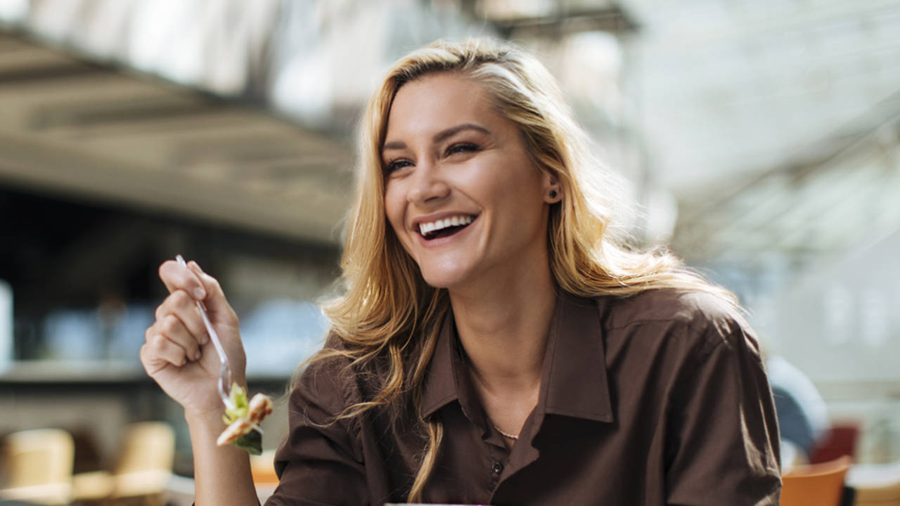 mujer comiendo sano sentada a la mesa sonriendo