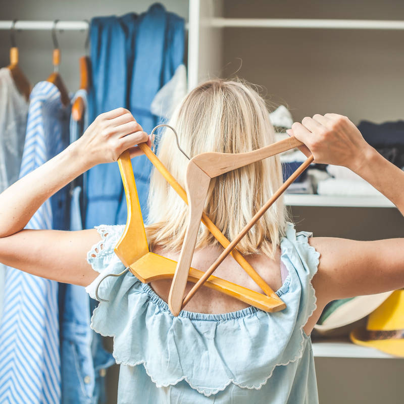 mujer de espaldas frente a un armario de ropa abierto