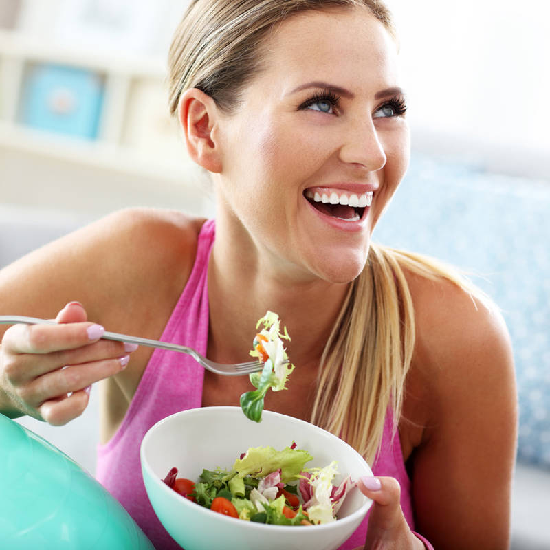 Mujer feliz comiendo ensalada