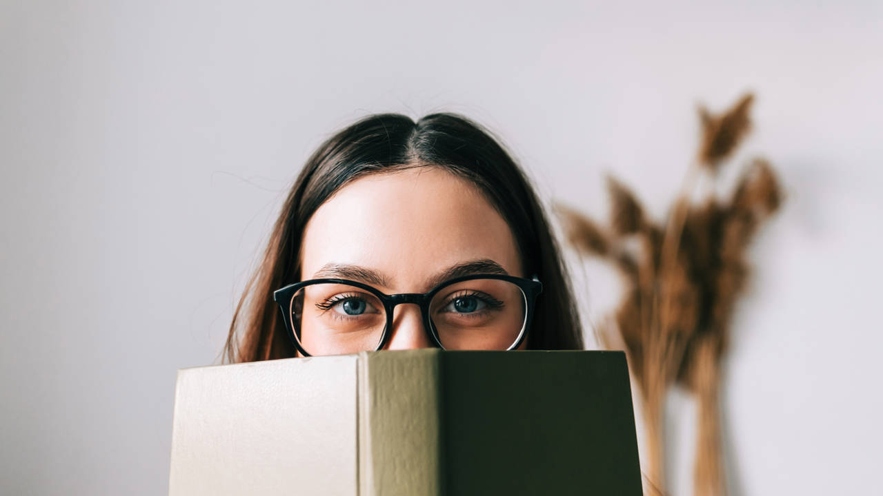 Mujer con gafas asoma tras libro