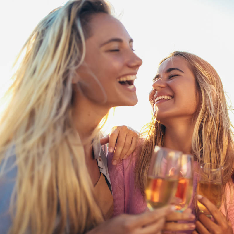 mujeres jovenes felices bebiendo vino alcohol