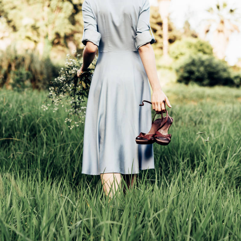 mujer descalza de espaldas caminando por la hierba