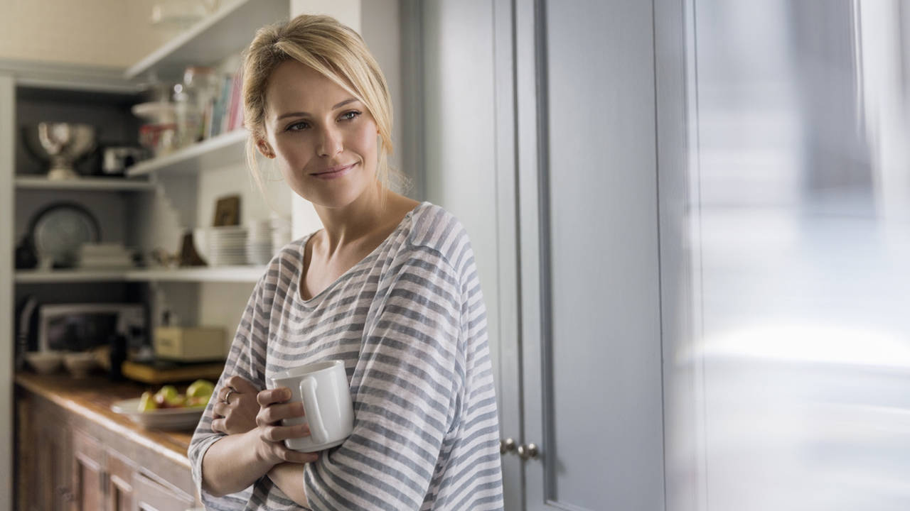 mujer en cocina con una taza en la mano