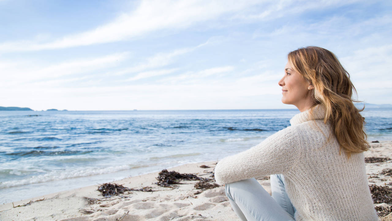 mujer tranquila serena mirando al mar en la playa