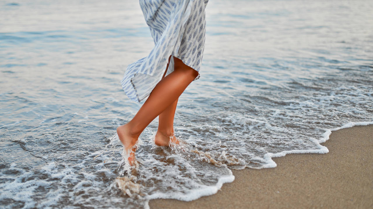 mujer caminando por la playa medio cuerpo piernas