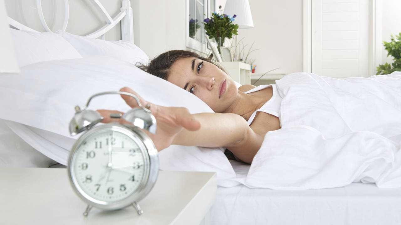 mujer en la cama reloj despertador