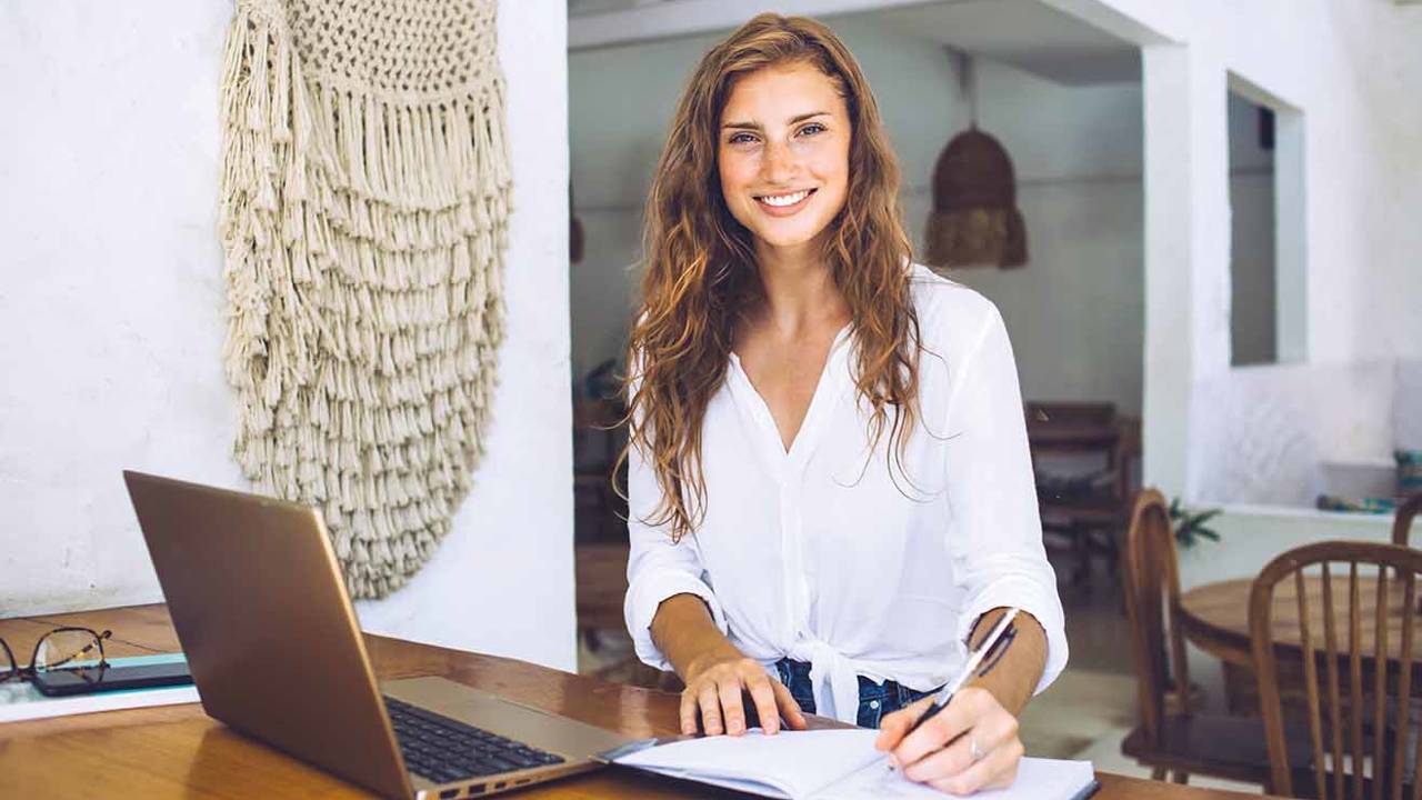 mujer joven sonriendo escribiendo ordenador verano