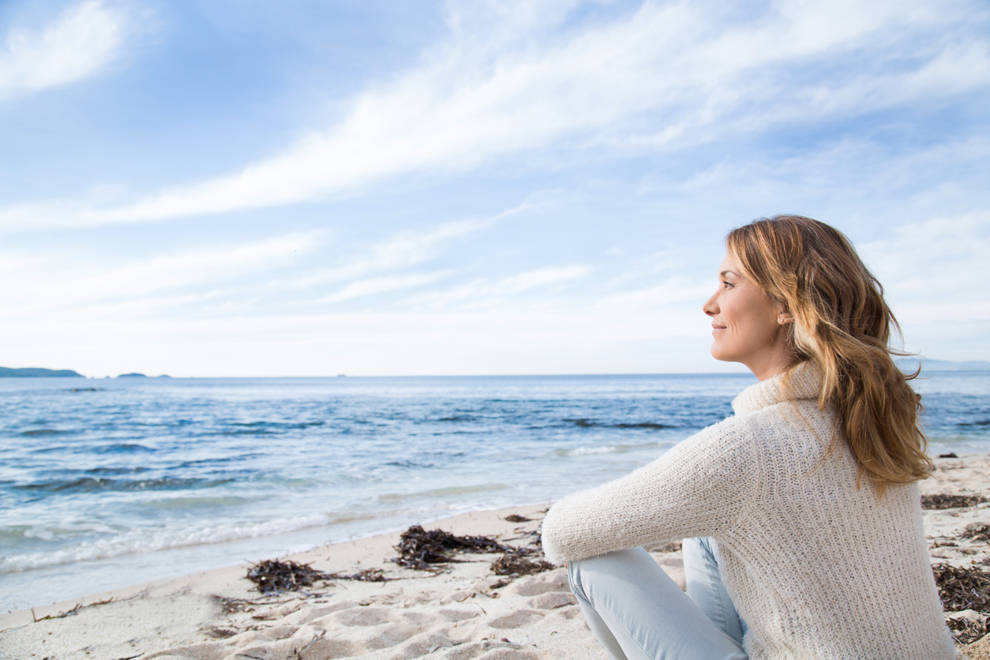 mujer tranquila serena mirando al mar en la playa