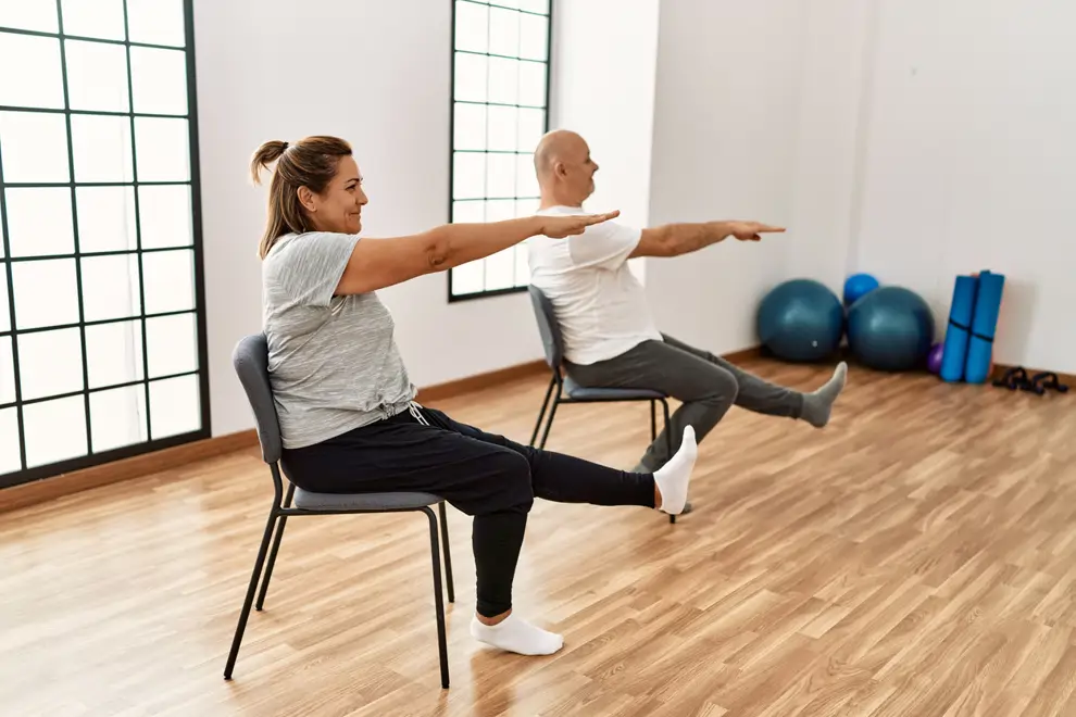 Home y mujer hacen ejercicio en silla