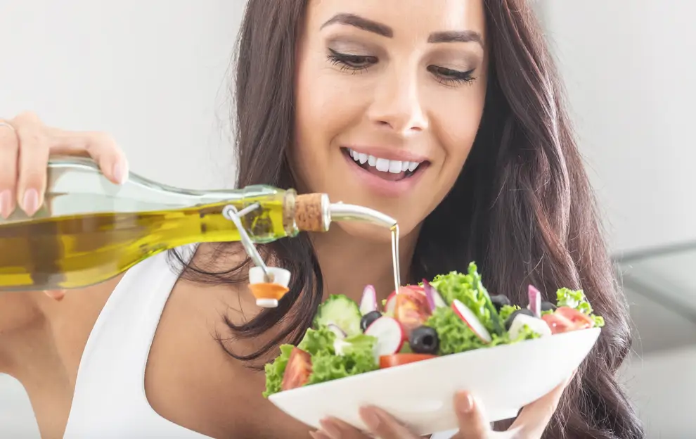 chica pone aceite en ensalada