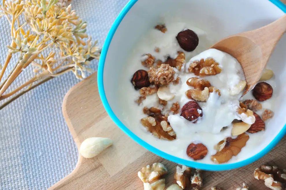Cuchara de yogur natural con nueces en un tazón
