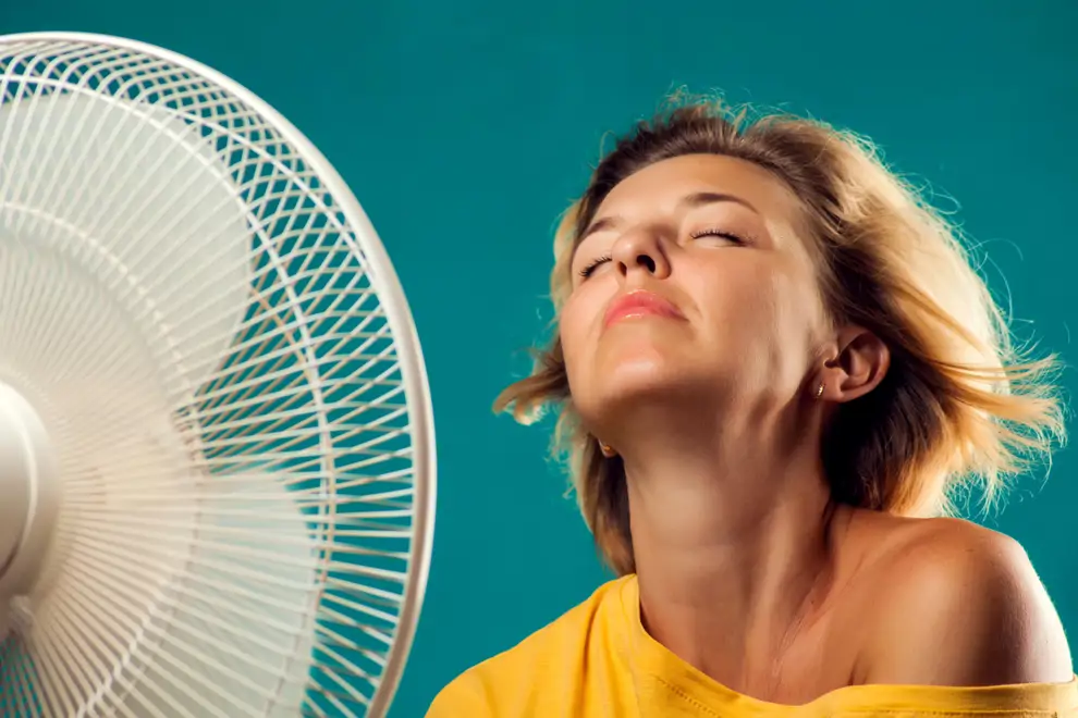 Un retrato de mujer frente a un ventilador que sufre de calor